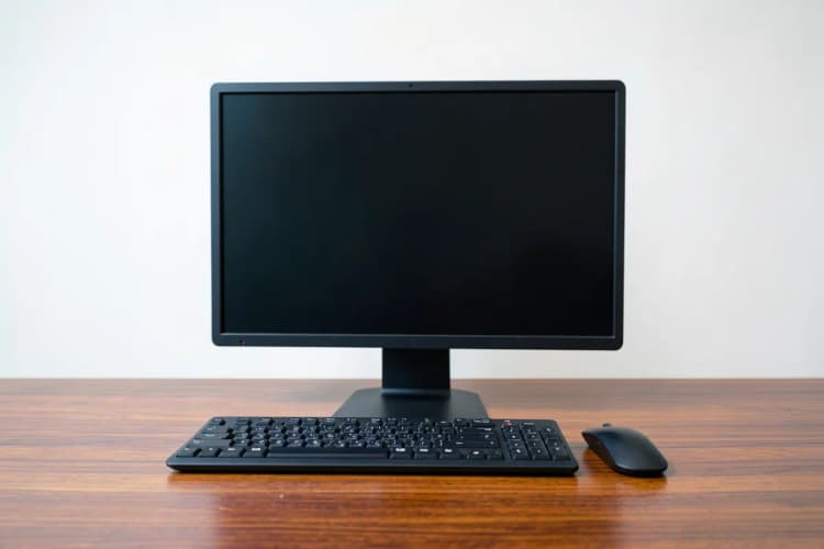 Um computador desligado com um teclado e um mouse sobre uma mesa de madeira, simbolizando a ausência de dados.
