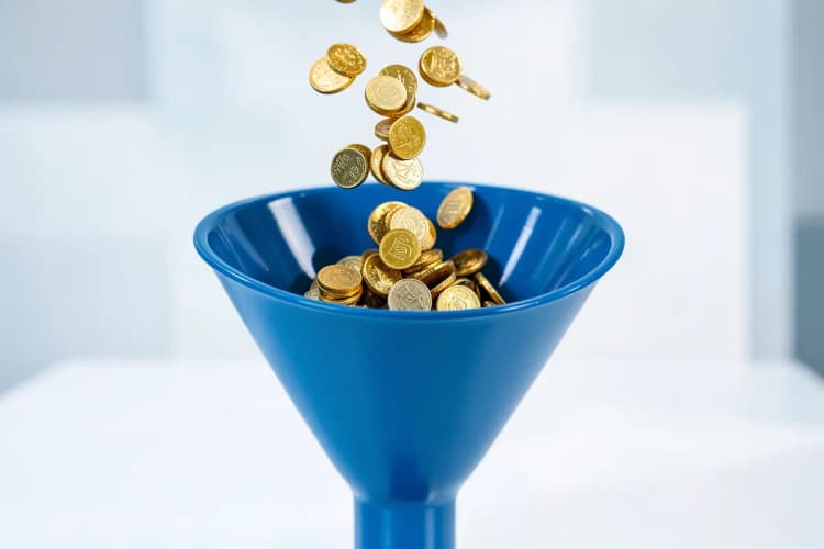 Moedas de ouro caindo em um funil, representando o investimento inicial.