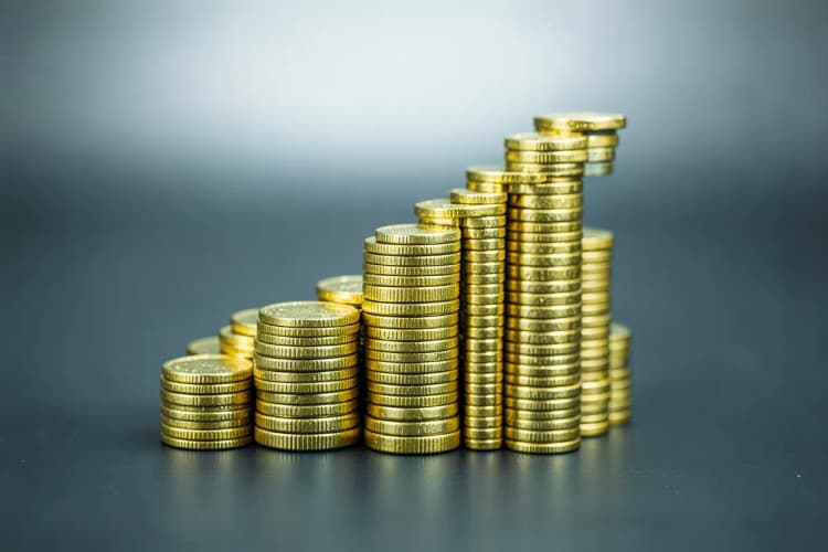 Um gráfico de barras subindo com moedas de ouro ao redor.