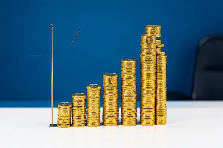 Um gráfico de barras ascendente feito de moedas de ouro em um fundo azul.