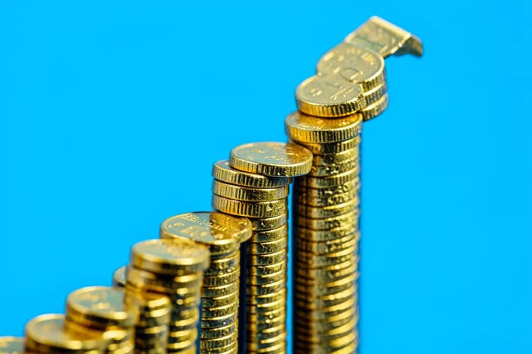 Um gráfico de barras ascendente feito de moedas de ouro em um fundo azul.