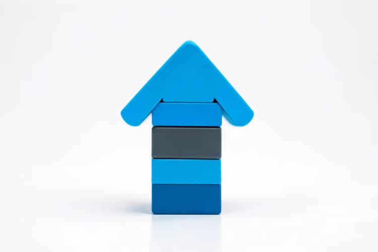 Um conjunto de blocos de construção coloridos formando uma seta apontando para cima, simbolizando crescimento e progresso.
