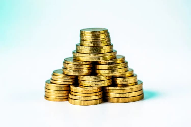 Moedas de ouro empilhadas em forma de pirâmide, simbolizando investimento e retorno.